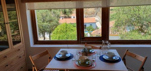 uma mesa de jantar com cadeiras, uma mesa e 2 janelas em Casa do Pássaro em Galegos