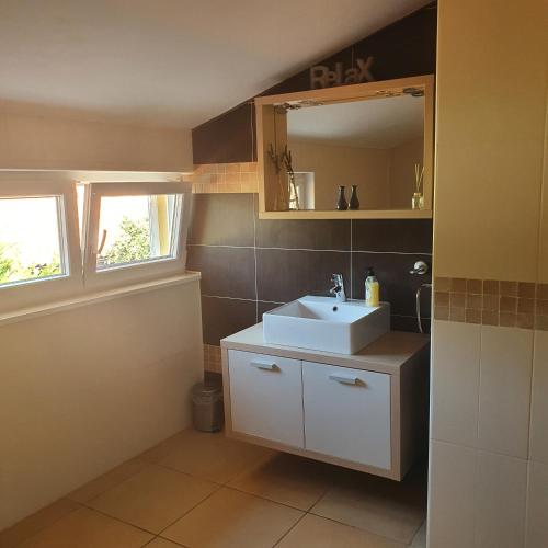a bathroom with a white sink and a mirror at Dee's House and Pool in Labin