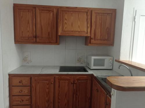 een keuken met houten kasten en een magnetron bij Apartamento Marlayo in Cala Blanca