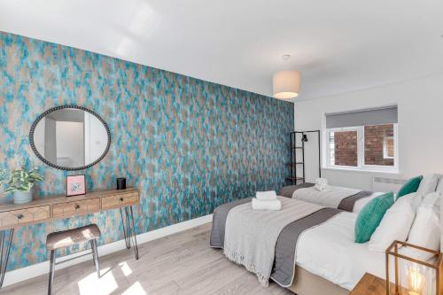a bedroom with two beds and a mirror at We Stay Baxter Gate in Loughborough