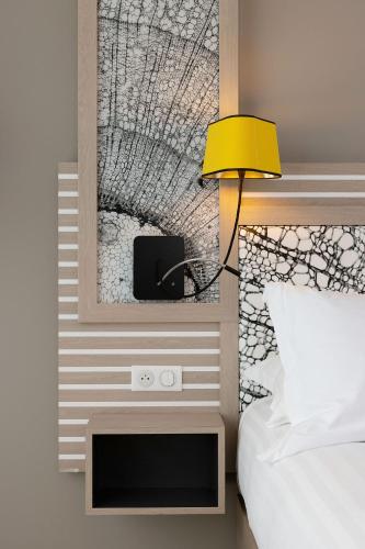 a bedroom with a mirror above a bed and a yellow lamp at Hilton Garden Inn Bordeaux Centre in Bordeaux