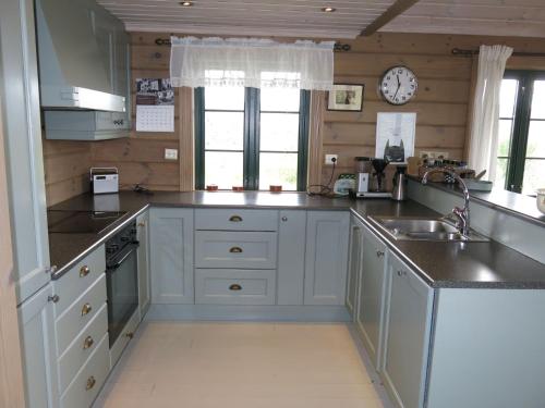 a kitchen with white cabinets and a clock on the wall at Holiday Home Brandsbu - SOW097 by Interhome in Åseral