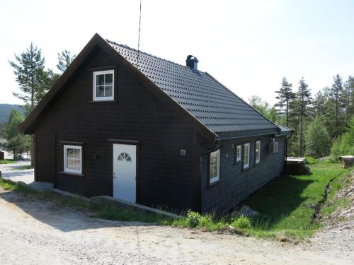 a black house with a white door on a dirt road at Holiday Home Revenbu by Interhome in Fossdal