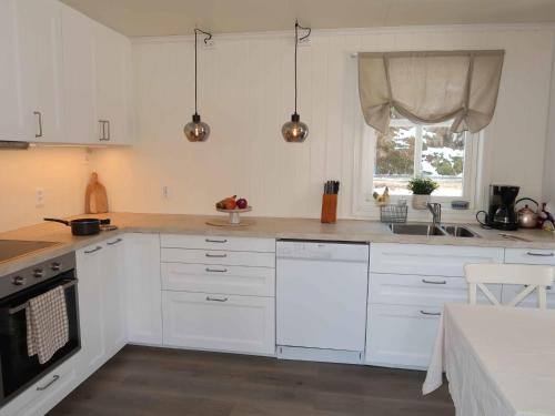 een keuken met witte kasten, een wastafel en een raam bij Holiday Home Furuholmen - FJS293 by Interhome in Lavik