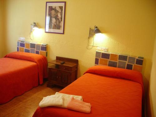 2 camas en una habitación con sábanas de color naranja en Hospedaje Senda del Huerna en Campomanes