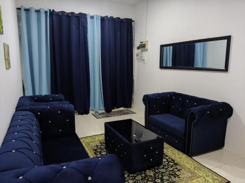 a living room with blue couches and a tv at Amisya Homestay in Kampung Raja