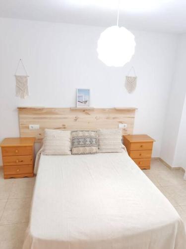 a bedroom with a large white bed and two night stands at Piso en Playa de Gandía! in Gandía