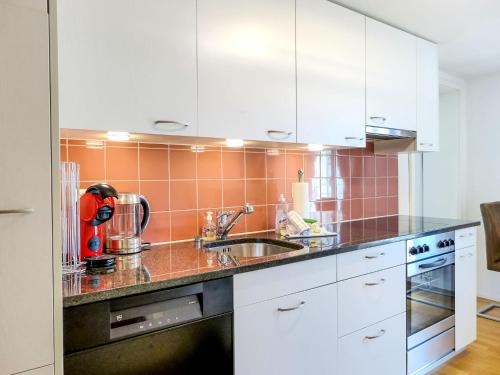 una cocina con armarios blancos y fregadero en Apartment Orya by Interhome, en Interlaken