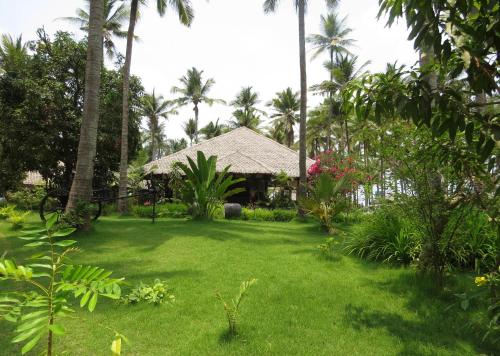 a garden with a house with palm trees and grass at Emerald Sea Resort in Ngwesaung