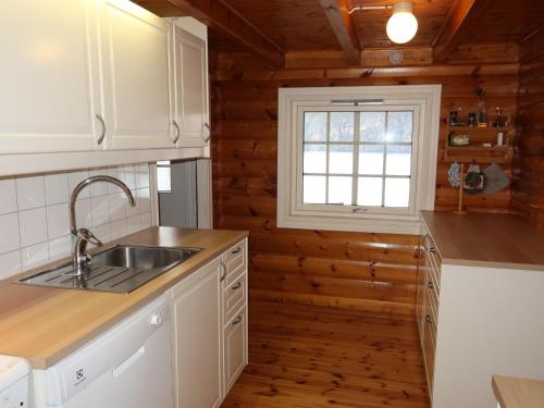 kuchnia z białymi szafkami, umywalką i oknem w obiekcie Chalet Krampehaugen - FJS046 by Interhome w mieście Utvik