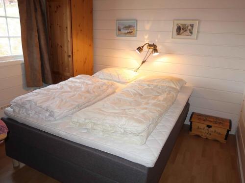 Chalet Hagehytta - FJS047 by Interhome في Utvik: سرير غير مرتب في غرفة النوم مع مصباح