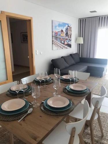 a dining room table with plates and wine glasses on it at Praia da Vagueira - Lights, Sea, Action! in Gafanha da Boa Hora