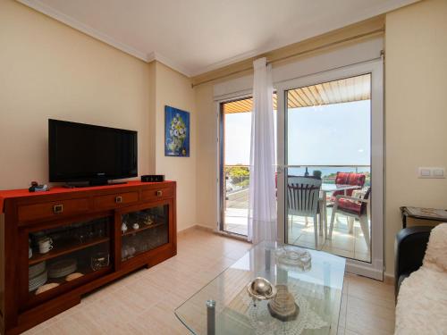 ein Wohnzimmer mit einem TV und einem Glastisch in der Unterkunft Apartment Sabater 17 by Interhome in Calpe