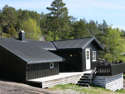 a black and white building with a wooden deck at Chalet Engelbu - SOW141 by Interhome in Fossdal