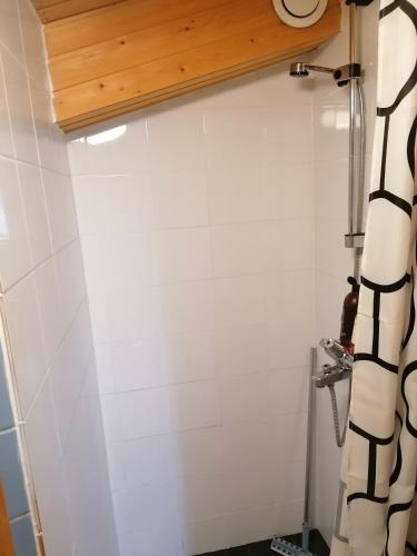 a bathroom with white walls and a black and white shower curtain at Lissun Majoitus in Alavieska