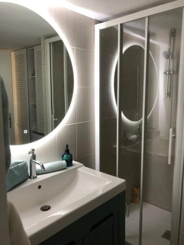 une salle de bain avec un lavabo, un miroir et une douche dans l'établissement Villa Clade: Chaleureuse et agréable maison de plage, à Lacanau-Océan