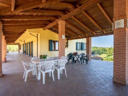 een patio met witte stoelen en tafels en een bakstenen plafond bij Holiday Home Ex I vigneti del mandorlo by Interhome in Mombaruzzo
