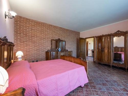 a bedroom with a pink bed and a brick wall at Holiday Home Lydia by Interhome in Mombaruzzo