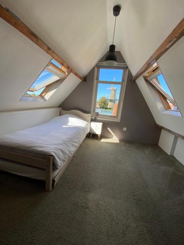 1 dormitorio en el ático con cama y ventana en Tiara, en Zierikzee