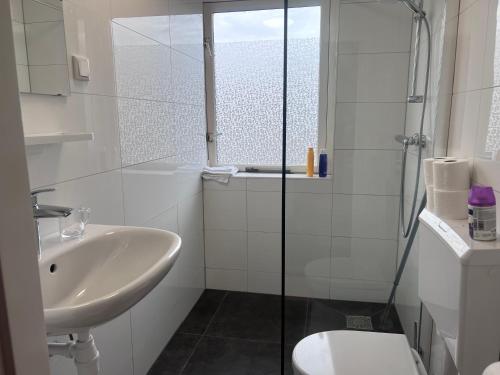 y baño blanco con lavabo y ducha. en Family Studio-Barendrecht en Barendrecht