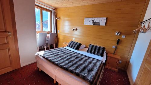 a bedroom with a bed and a wooden wall at Hotel Christiania in La Clusaz