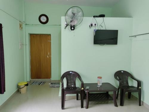 Habitación con 2 sillas, mesa y ventilador en KUKKE GUEST ROOM, en Subrahmanya