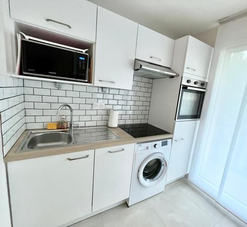 a white kitchen with a sink and a dishwasher at Vacances paradisiaques à la plage in Deauville
