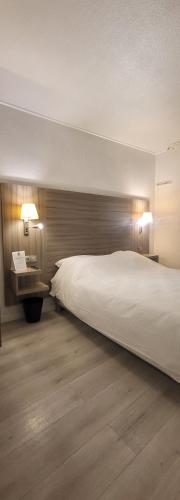 a bedroom with a large white bed and a desk at Crystal Hotel Saint Denis Basilique in Saint-Denis