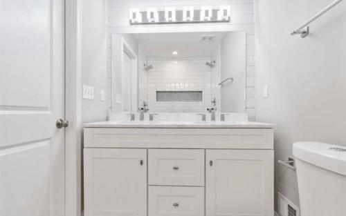 a white bathroom with a sink and a mirror at The Blue House! Modern+ Rooftop deck+ Parking in Baltimore