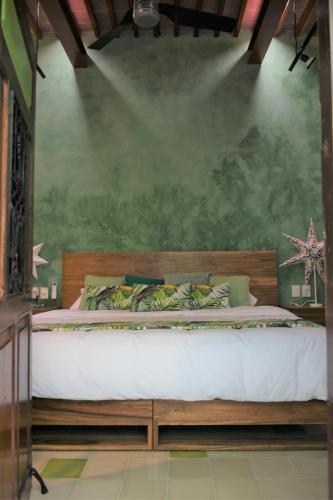 a bed in a bedroom with a green wall at Trilliza-Verde in Campeche