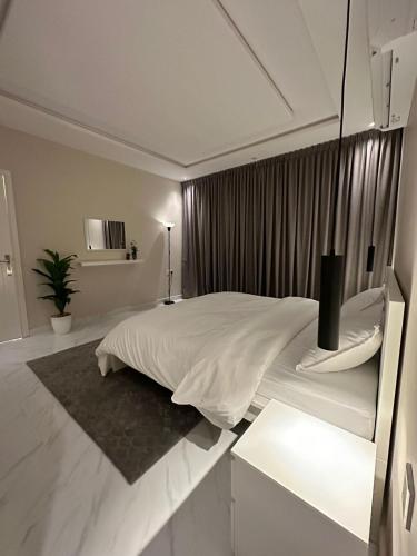 a white bedroom with a large bed and a window at شقة مودرن في حي العقيق in Riyadh