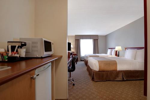 um quarto de hotel com duas camas e uma secretária com uma televisão em Days Inn by Wyndham Dawson Creek em Dawson Creek