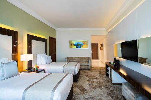 a hotel room with two beds and a flat screen tv at Elite Byblos Hotel in Dubai