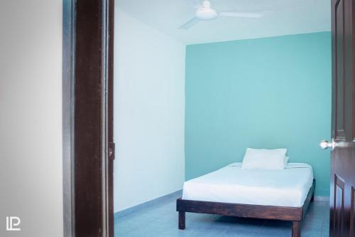 1 dormitorio con cama blanca y pared azul en Hotel Quiam en Playa del Carmen