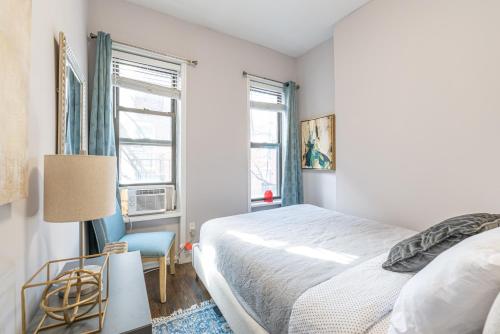 a bedroom with a bed and a chair and windows at 3BR Chelsea in NYC in New York