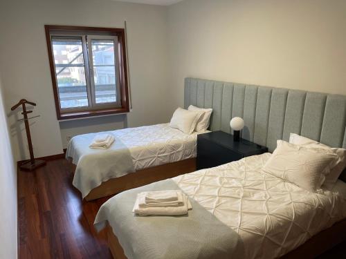 a bedroom with two beds and a window at Home of Neptune in Póvoa de Varzim