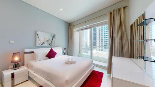 Un dormitorio con una cama blanca y una ventana grande. en Marina Heights - Unique One Bedroom, en Dubái