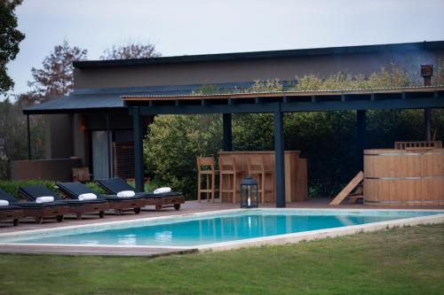 una piscina con cenador y sillas junto a ella en Posada Campotinto, en Carmelo