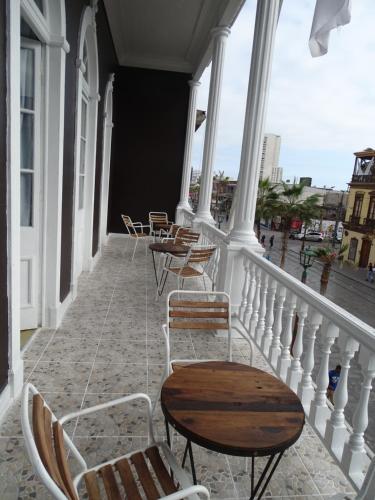 Un balcón con sillas y mesas en un edificio en Gran Casona Hostal, en Iquique