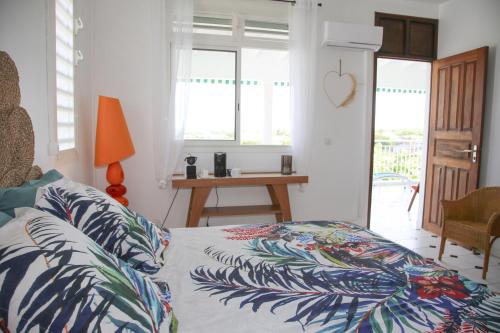 a bedroom with a bed with a tropical patterned sheets at Villa Théo , chambre d'hôtes , petit déjeuner, table d'hôtes in Sainte-Anne