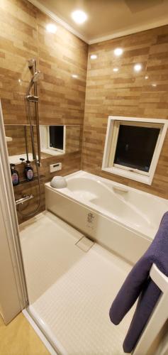 baño con bañera y TV. en CANAL HOUSE BOSTONS, en Niigata