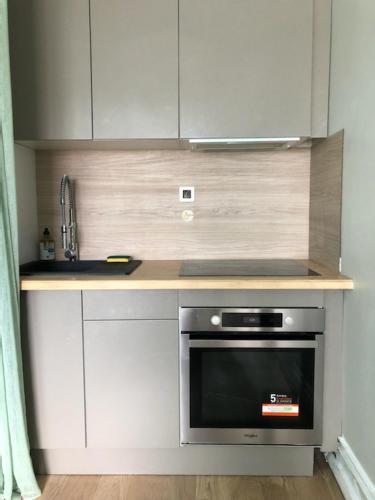 une cuisine avec des armoires blanches et un four noir dans l'établissement soleil et bateau, à Courseulles-sur-Mer