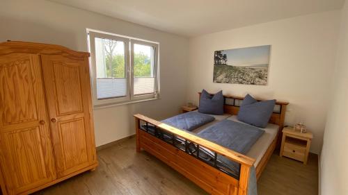 a bedroom with a large wooden bed with blue pillows at Klönhüsing in Altefähr