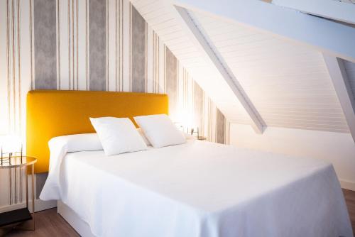 a bedroom with a white bed with a yellow headboard at CASIVERDE APARTAMENTO in Córdoba