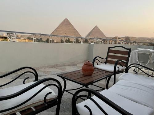 two beds and a table on a balcony with pyramids at La Perle Pyramids in Cairo