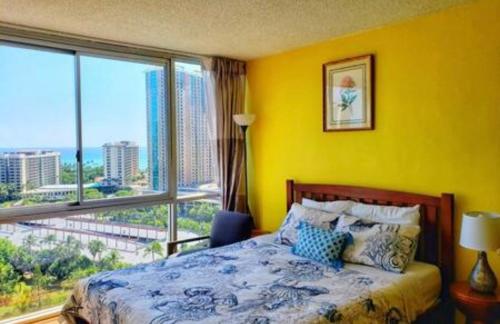 um quarto amarelo com uma cama e uma grande janela em Soothing Hawaii Condo - 18F em Honolulu