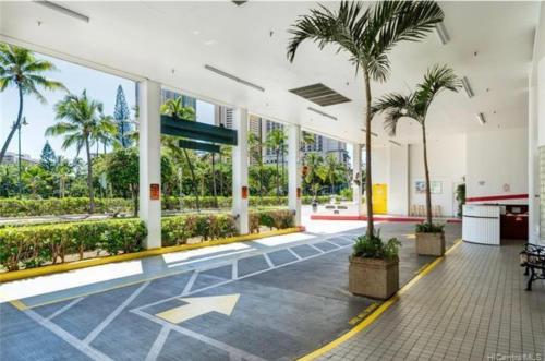 a lobby with palm trees in a building at Soothing Hawaii Condo - 18F in Honolulu