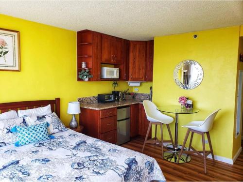1 dormitorio con paredes amarillas, 1 cama y cocina en Soothing Hawaii Condo - 18F, en Honolulu