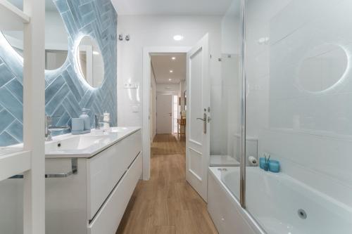 a white bathroom with a shower and a sink at Casa Augusto - junto al Teatro Romano, con garaje in Merida