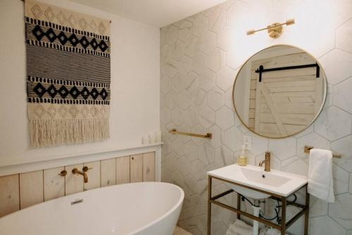 ein Badezimmer mit einer Badewanne, einem Waschbecken und einem Spiegel in der Unterkunft Downtown Studio 3 at Beer Ranch Project Inn in Wimberley